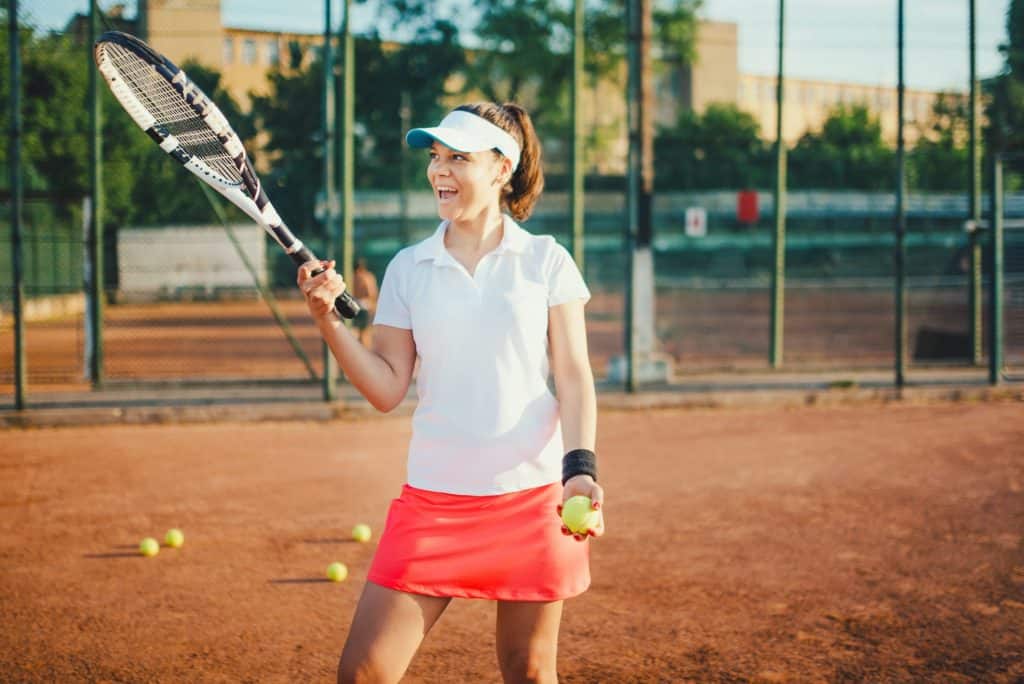 young tennis player, sportswoman on clay court with racquet and balls.