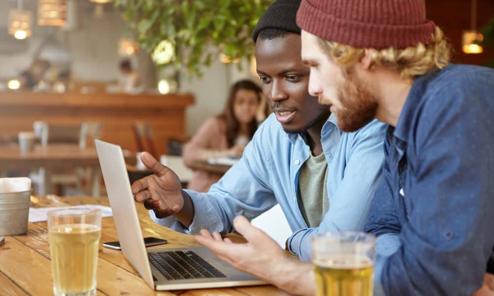 Business partners meeting together at cafeteria, developing business strategy using laptop computer,
