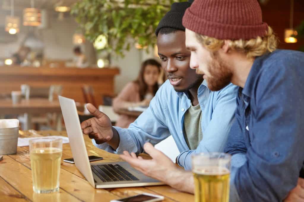 Business partners meeting together at cafeteria, developing business strategy using laptop computer,