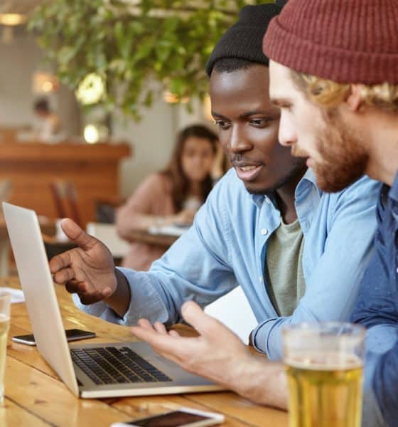 Business partners meeting together at cafeteria, developing business strategy using laptop computer,